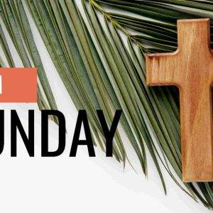 Wooden cross on palm leaves background for Palm Sunday.