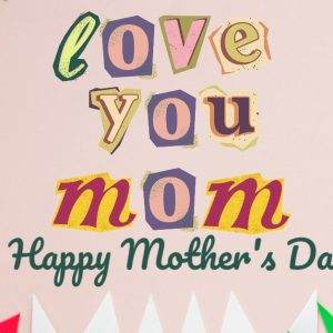 Colorful Mother's Day card with "Love You Mom" message on pink paper background surrounded by vibrant paper designs.