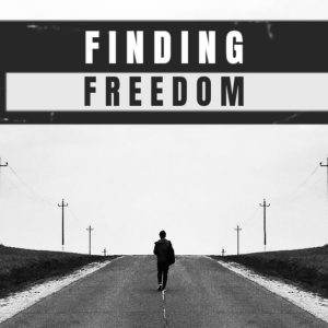 Silhouette of a person walking alone on a wide road with power lines, under the bold text 'Finding Freedom'.