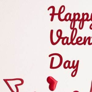 Festive Happy Valentine's Day greeting with scattered red hearts on a plain background