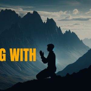 Person praying with mountains in the background, silhouette at dusk.