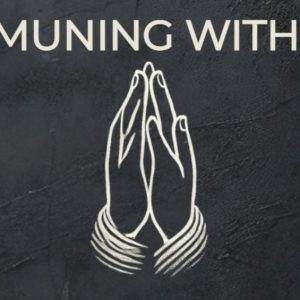 Hands in prayer on a textured black background with the words "Communing with God"