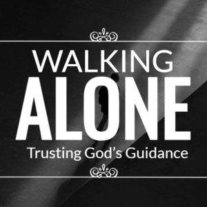 Person walking alone in dim light with text overlay 'Walking Alone: Trusting God's Guidance'.