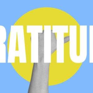 Hand reaching up with the word 'Gratitude' over blue and yellow background.