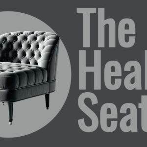 Luxurious gray tufted chair in a minimalistic design against a dark background promoting The Healing Seat.