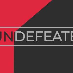 Bold graphic featuring the word 'UNDEFEATED' in gray on a red and black geometric background.