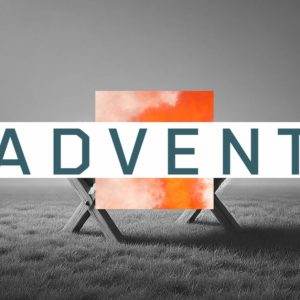 Wooden manger on a grassy field with a vibrant orange square and the word "Advent" in bold letters.